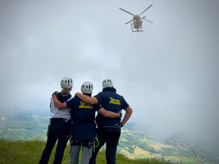 Trois soignants regardent l'hélicoptère dans le ciel